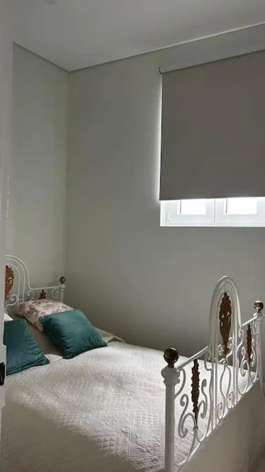 Vista do quarto com cama de ferro e janela