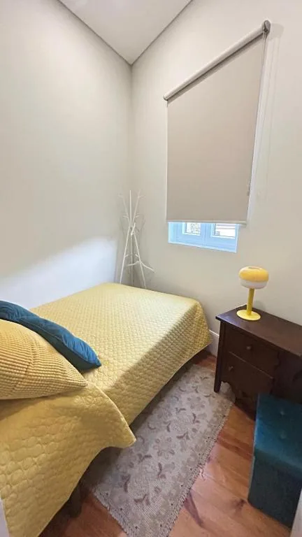 Quarto com colcha amarela e mesa de cabeceira